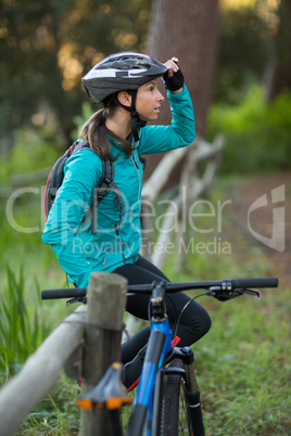 Female biker sitting on a fence in countryside