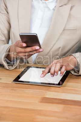 Mid-section of Businesswoman using mobile phone and digital tablet