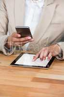 Mid-section of Businesswoman using mobile phone and digital tablet