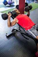 Man exercising with dumbbells on bench