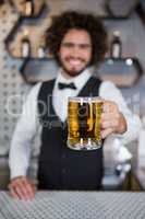 Bartender holding glass of beer in bar counter