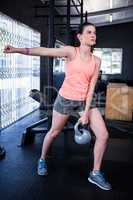 Young woman lifting kettlebell in gym
