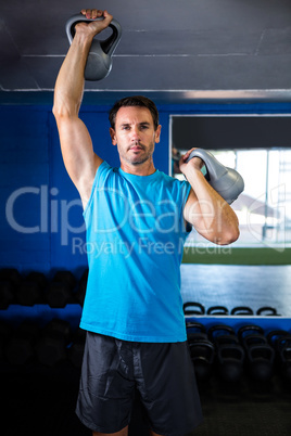 Portrait of young man holding kettlebell in gym