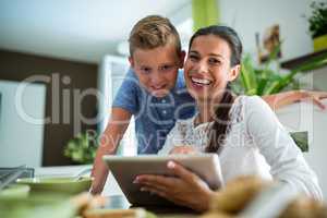 Mother and son using digital tablet in the living room