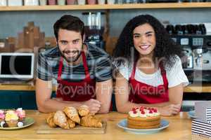 Portrait of waiter and waitress leaning on counter