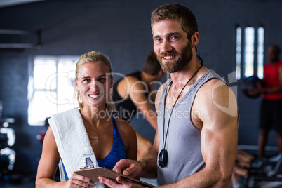 Portrait of smiling fitness instructor with woman in gym