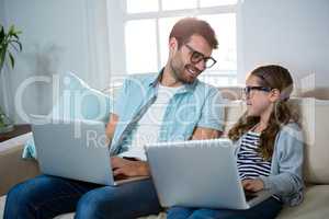 Father and daughter using laptop in the living room