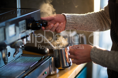 Waiter making cup of coffee at counter in kitchen