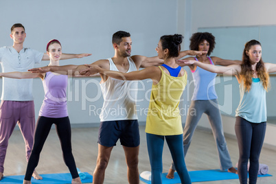 Yoga instructor helping student with a correct pose