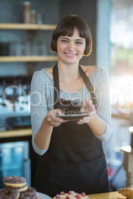 Portrait of waitress holding cup of coffee