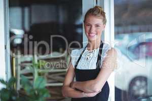 Portrait of smiling waitress standing with arms crossed