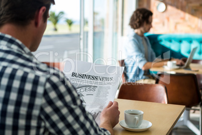 Man reading a business newspaper in coffee shop