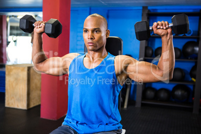 Determined athlete exercising with dumbbells