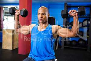 Determined athlete exercising with dumbbells