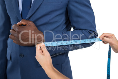 Mid section of woman measuring businessman sleeve