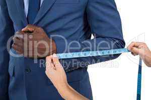 Mid section of woman measuring businessman sleeve