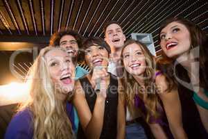 Group of friends singing song together in bar