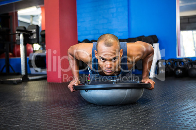 Portrait of stern male athlete with BOSU ball in gym