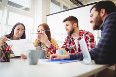Photo editor showing documents to coworkers in meeting room