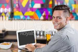 Smiling man using laptop in restaurant