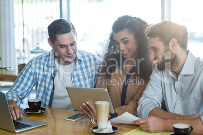 Friends using digital tablet and laptop in cafÃ?Â©