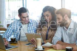 Friends using digital tablet and laptop in cafÃ?Â©