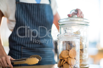 Waitress holding jar and tong in cafÃ?Â©