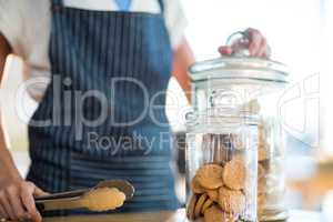 Waitress holding jar and tong in cafÃ?Â©