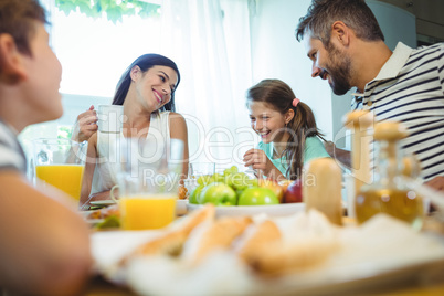 Smiling parents talking with their daughter at breakfast table