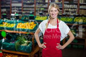 Smiling female staff standing with hand on hip in organic section