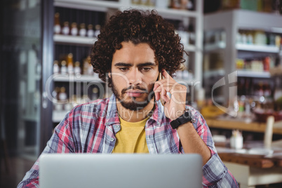 Man using laptop while talking on mobile phone Man using laptop while talking on mobile phone