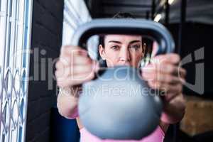 Serious female athlete lifting kettlebell in gym