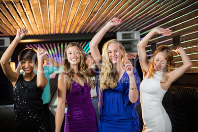 Group of smiling friends dancing on dance floor