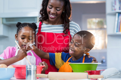 Children preparing cake with their mother