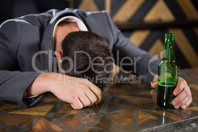 Drunk man lying on a counter with bottle of beer