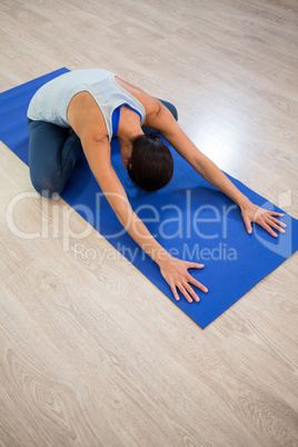 Woman doing cross legged forward fold on exercise mat