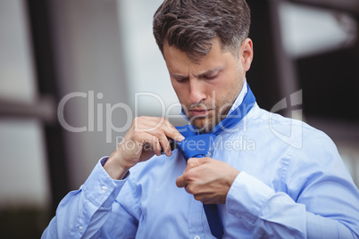 Handsome businessman adjusting his tie