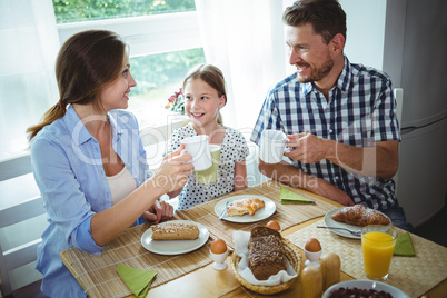 Family toasting a cup of coffee while having breakfast