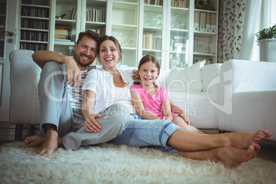 Happy family sitting on the rug in living room