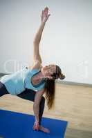 Woman performing extended side angle pose on exercise mat