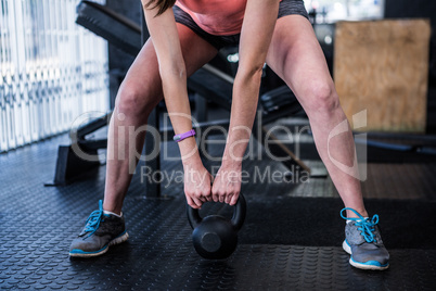 Low section of athlete holding kettlebell in gym