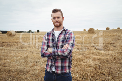 Portrait of farmer standing with arms crossed in the field