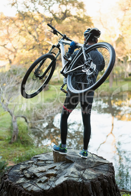 Male mountain biker carrying bicycle looking at nature