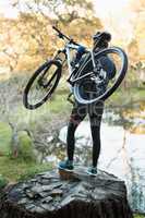 Male mountain biker carrying bicycle looking at nature
