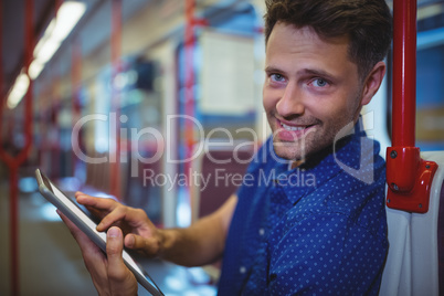 Portrait of handsome man using digital tablet in train