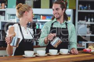 Smiling waiter and waitress making cup of coffee at counter