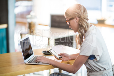 Woman using a laptop and mobile phone