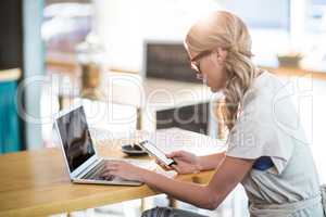 Woman using a laptop and mobile phone
