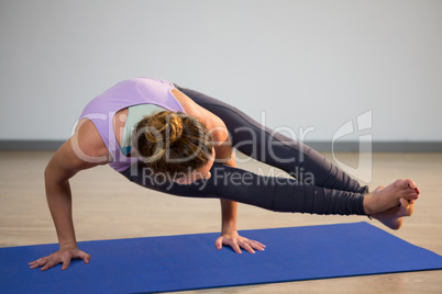Woman doing eight angle pose on exercise mat