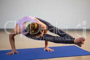 Woman doing eight angle pose on exercise mat